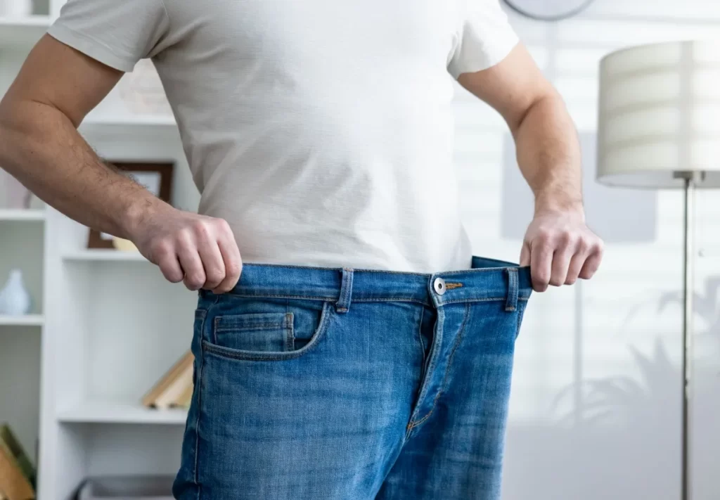 man showing weight loss by wearing loose jeans in utc